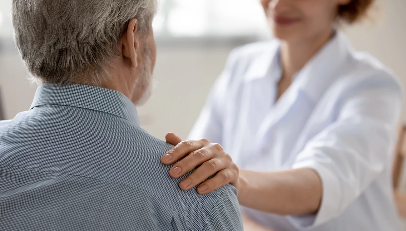 Ouder persoon met een verzorger. Hand op de schouder