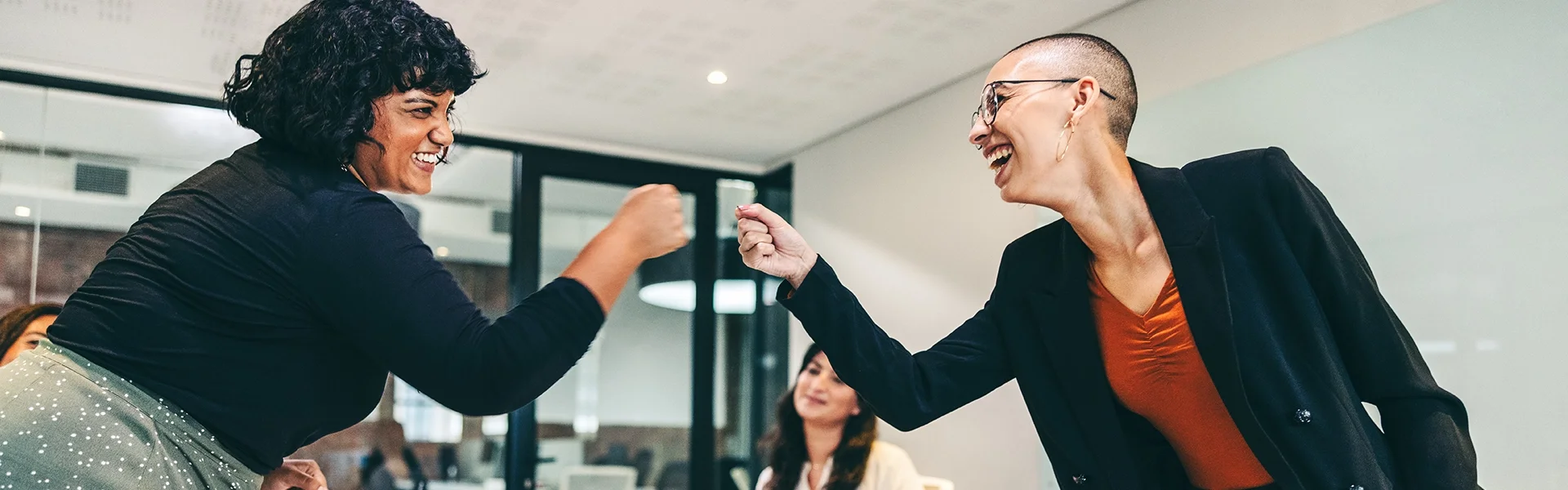 Twee personen geven elkaar een boks in een vergaderzaal
