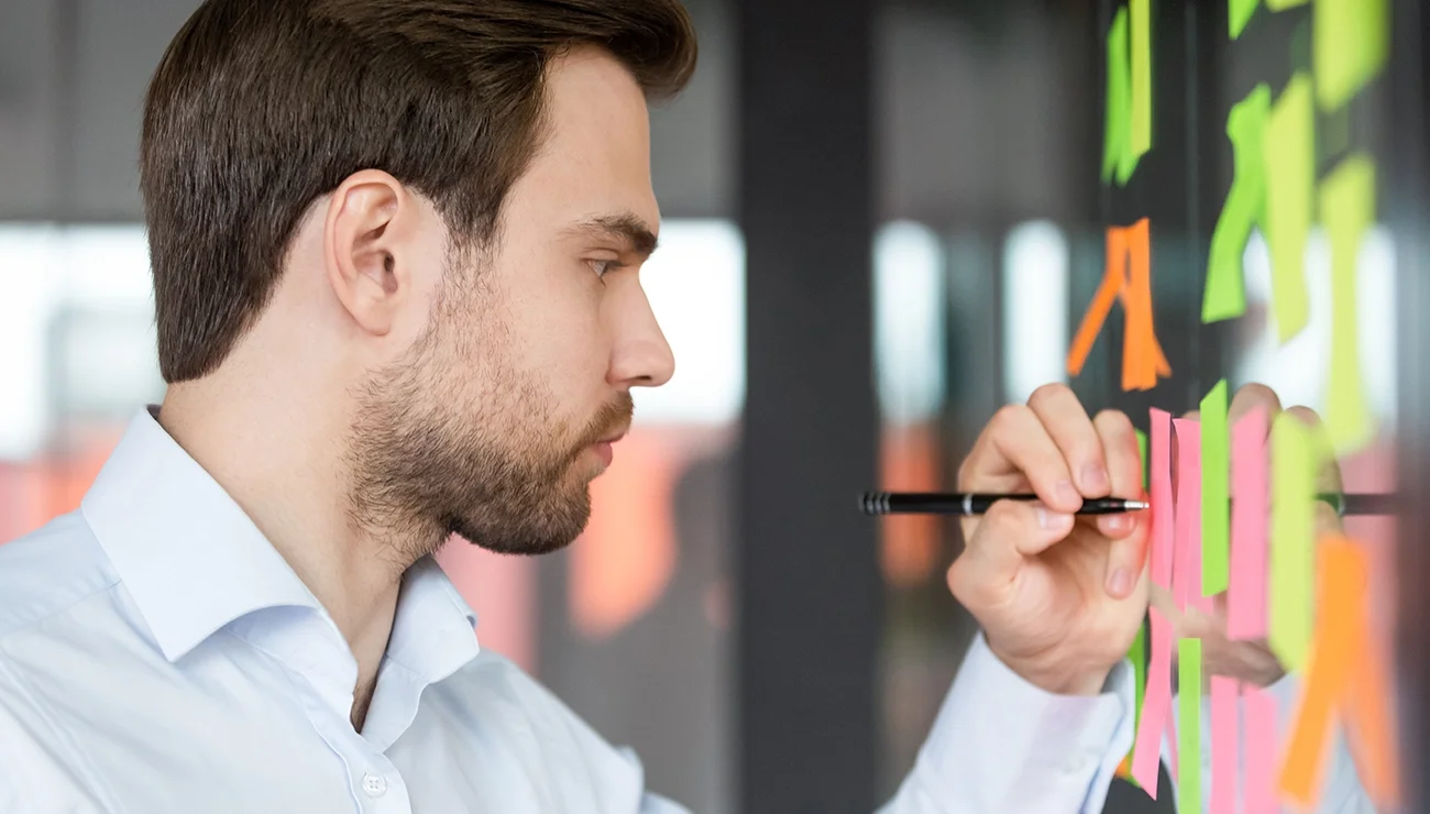 Man schrijft op bord met post its