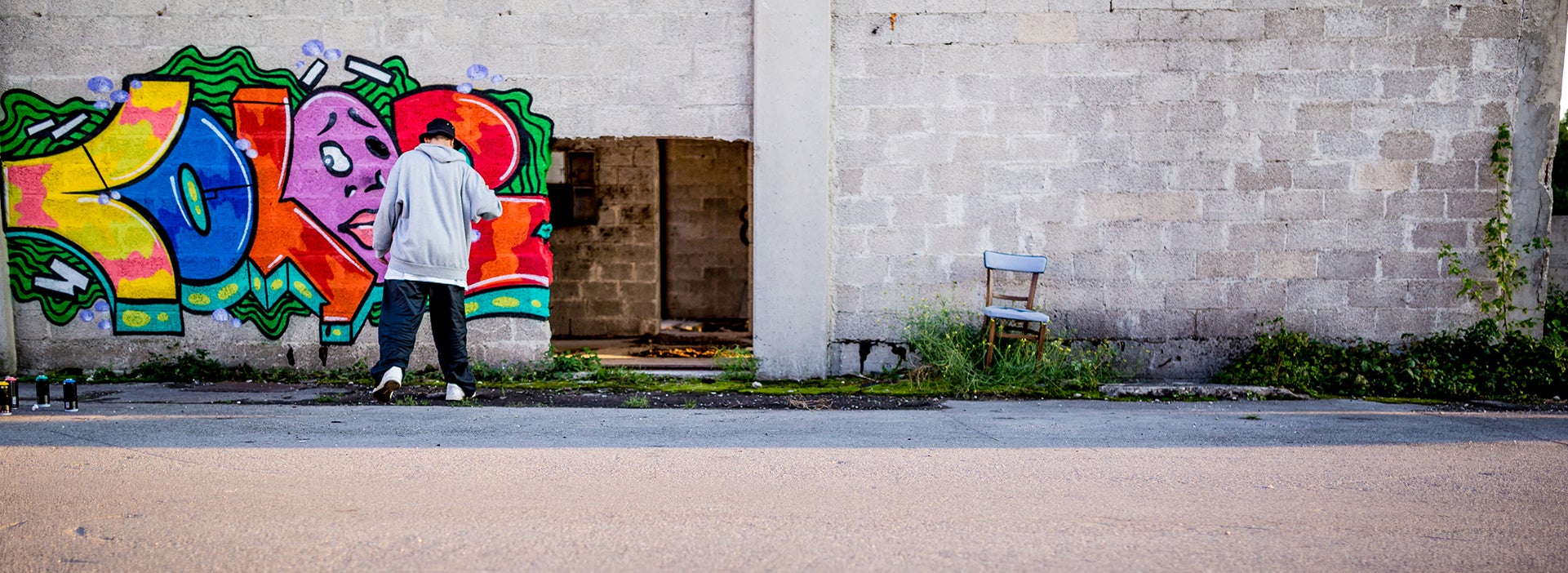 Persoon maakt graffitti op een grijze muur