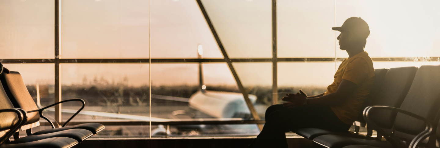 A man in a baseball cap sitting in an airport terminal
