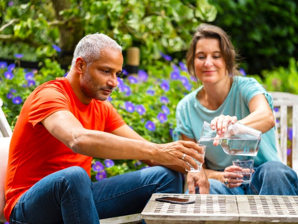 Man en vrouw drinken water in tuin