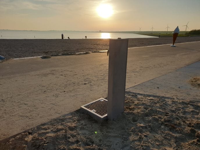 Drinkwatertappunt op het strand met een ondergaande zon