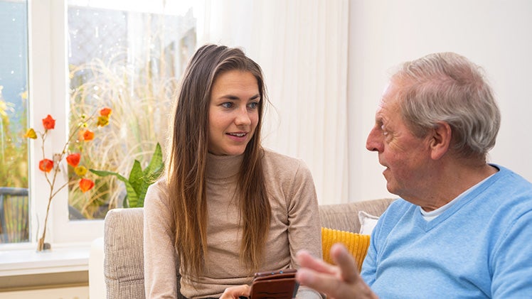Kleindochter helpt senioren man op bank