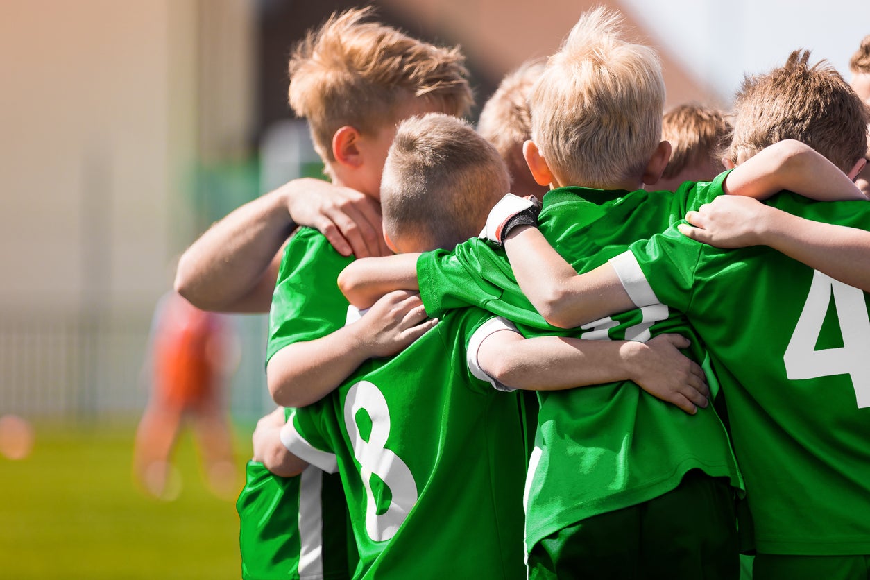A youth sports teams wearing green shirts huddle before a match