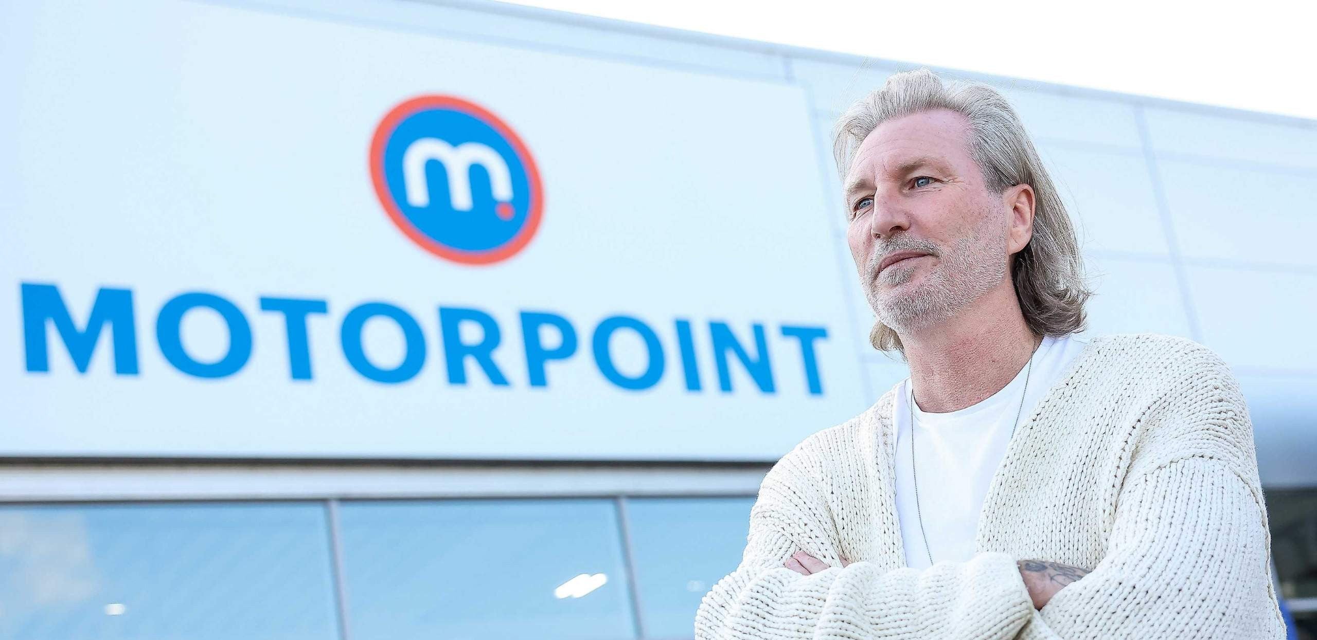 Image of Robbie Savage outside a Motorpoint store with store branding in the background