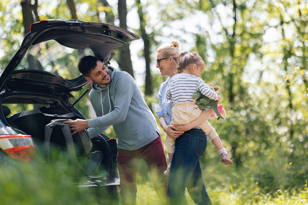 dad loading bags in boot whilst mother holds young child