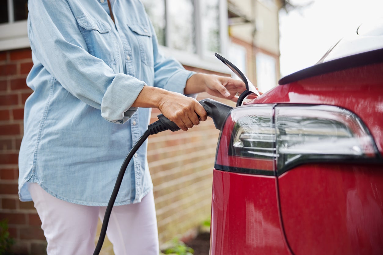 Image of woman plugging in EV charger into car