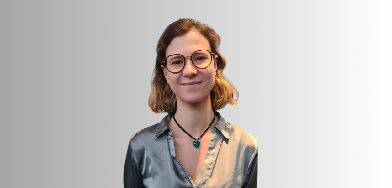 Michaela Kaneva poseert voor een witte muur. 