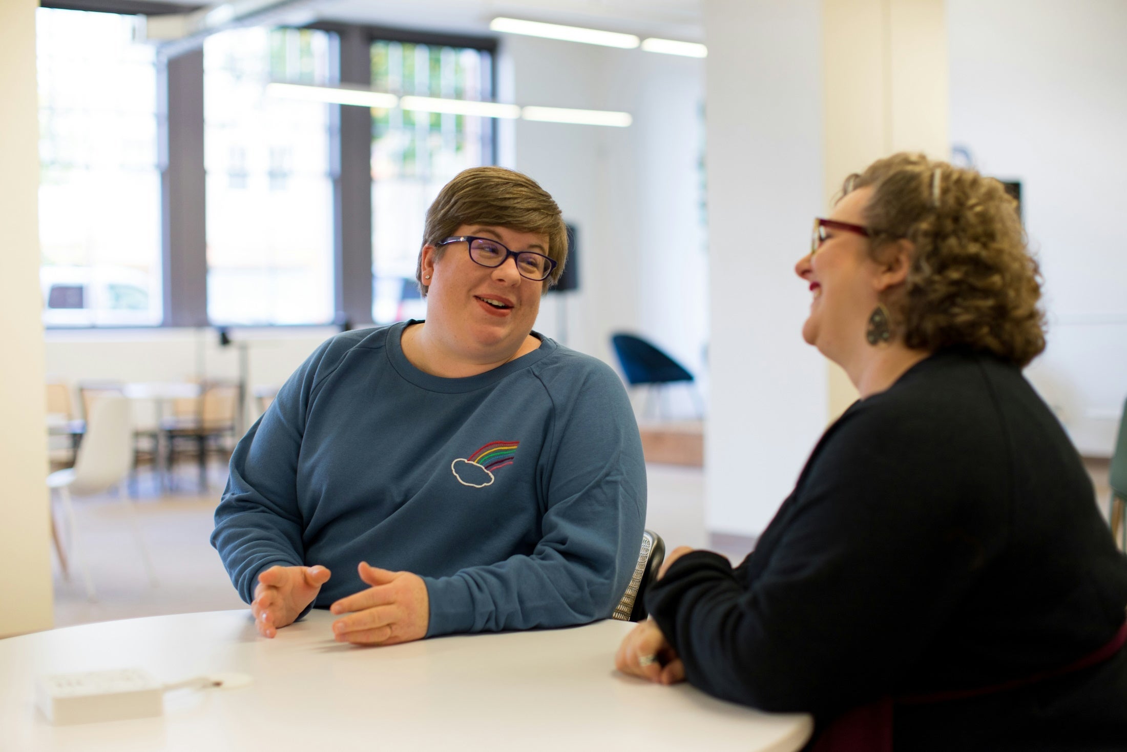 Two people in an office setting chatting pleasantly