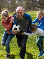 Een vader is met drie kinderen aan het voetballen