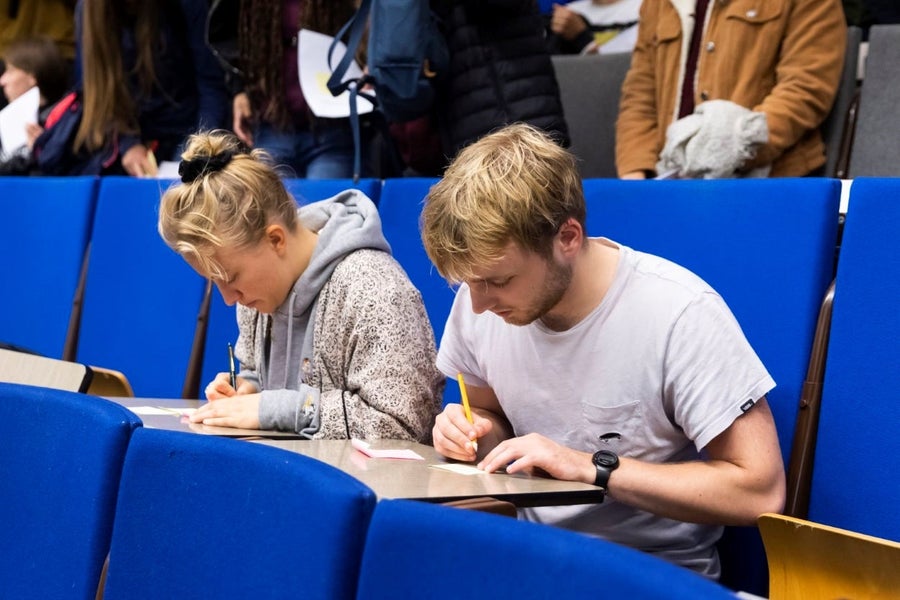 Two students work on a writing assignment in a lecture hall