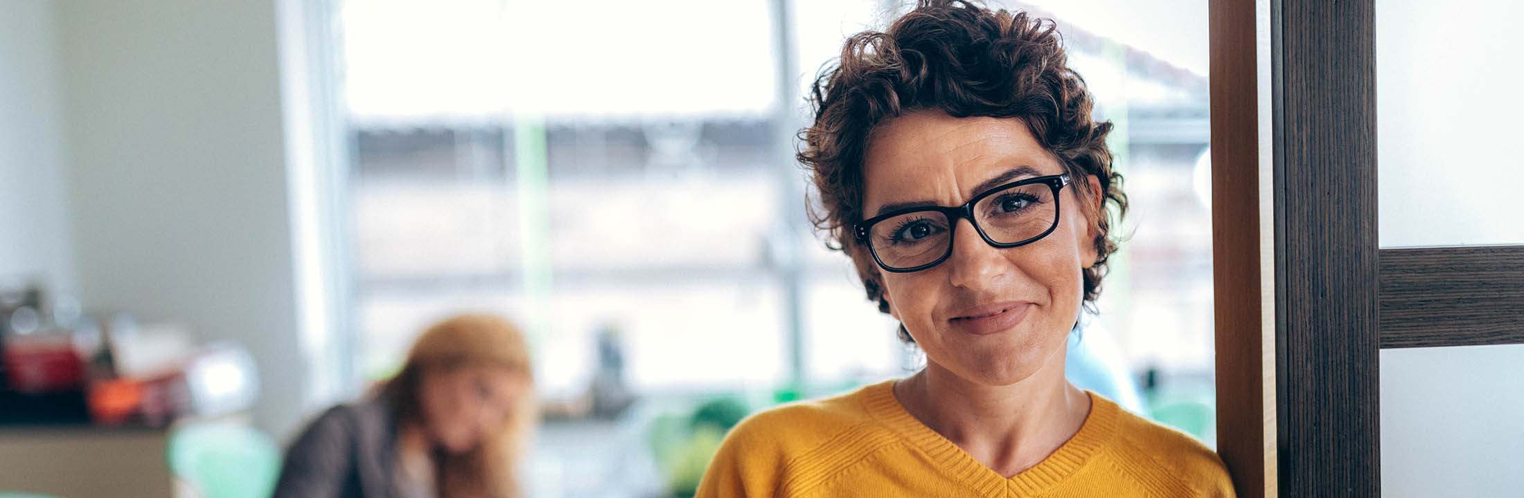 Dame met bril in camera kijkend gele trui Strategische Griffier