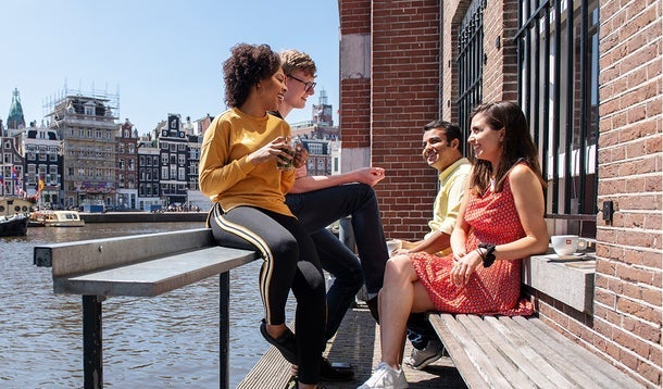 Four students are talking with each other besides an Amsterdam canal