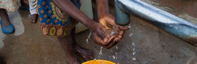Someone washing his hands under a primitive tap