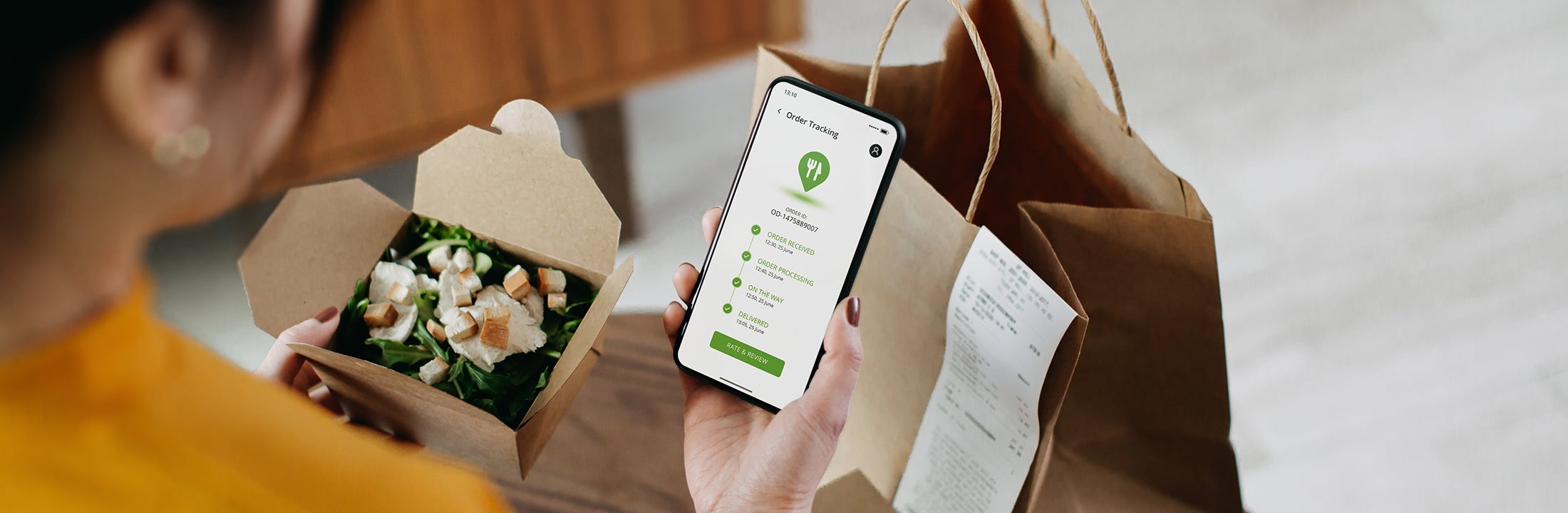 A woman holds a salad and a phone