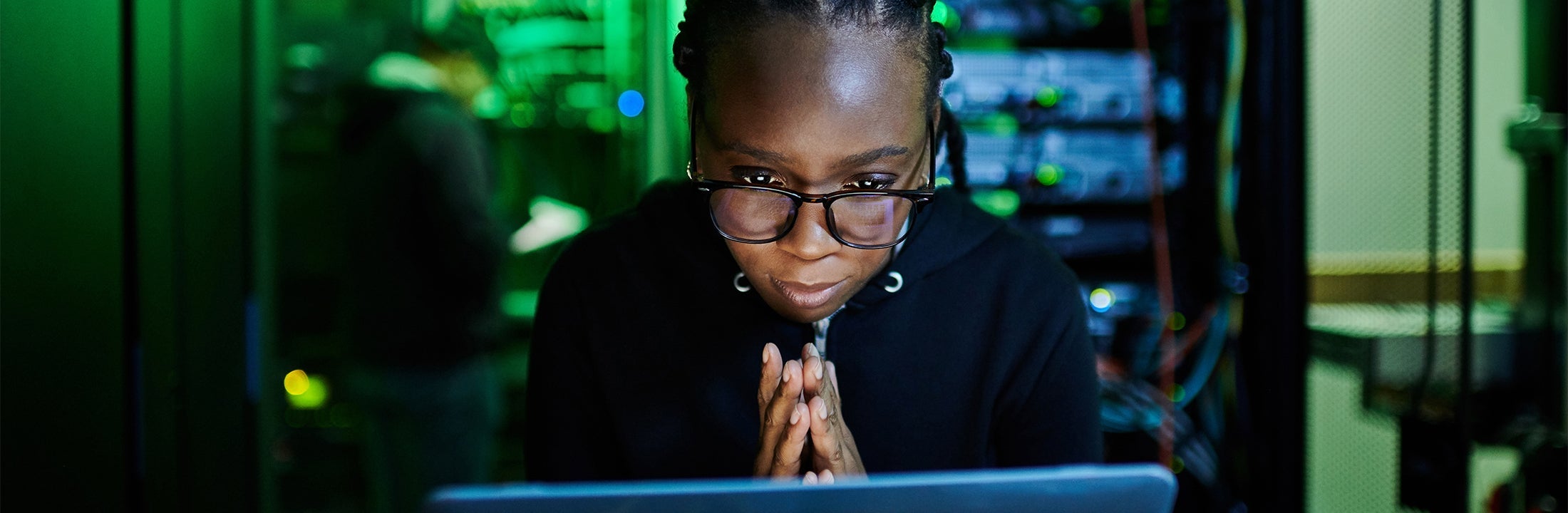 Someone sits behind a computer in a data centre