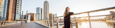 A woman on a bridge overlooking a river in an urban setting