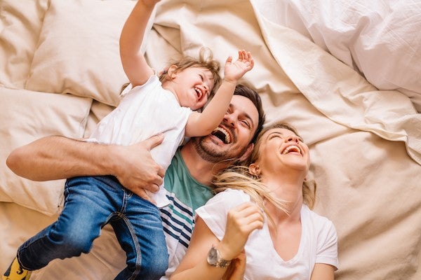 Family laughing on bed