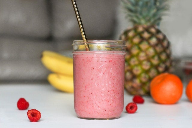 Pink smoothie is a jar with fruits around it