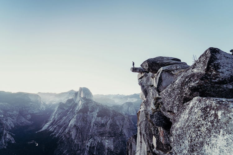 A person standing on a rocky outcrop in a mountainous area