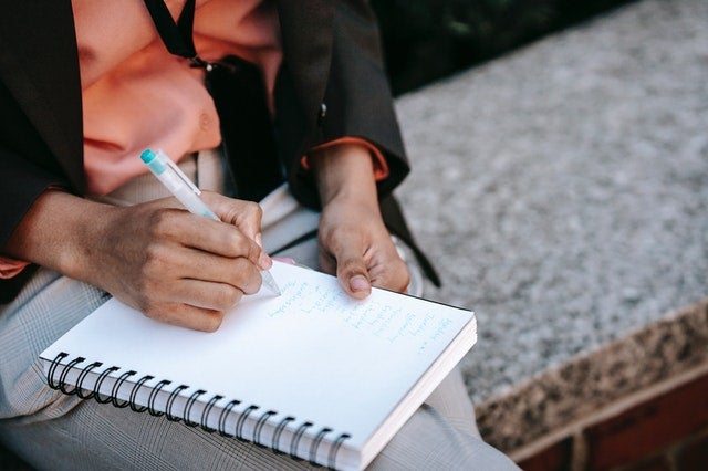 Woman sitting down writing in journal