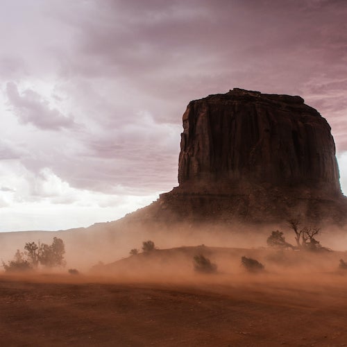 A dust storm in a desert, outlining a rocky outcrop
