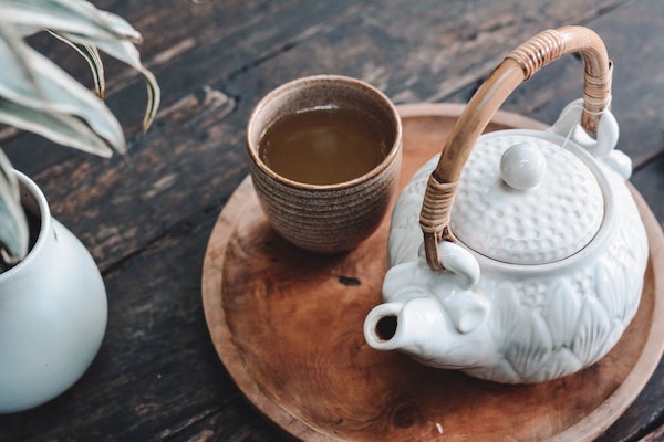 White teapot and clay cup on a tray