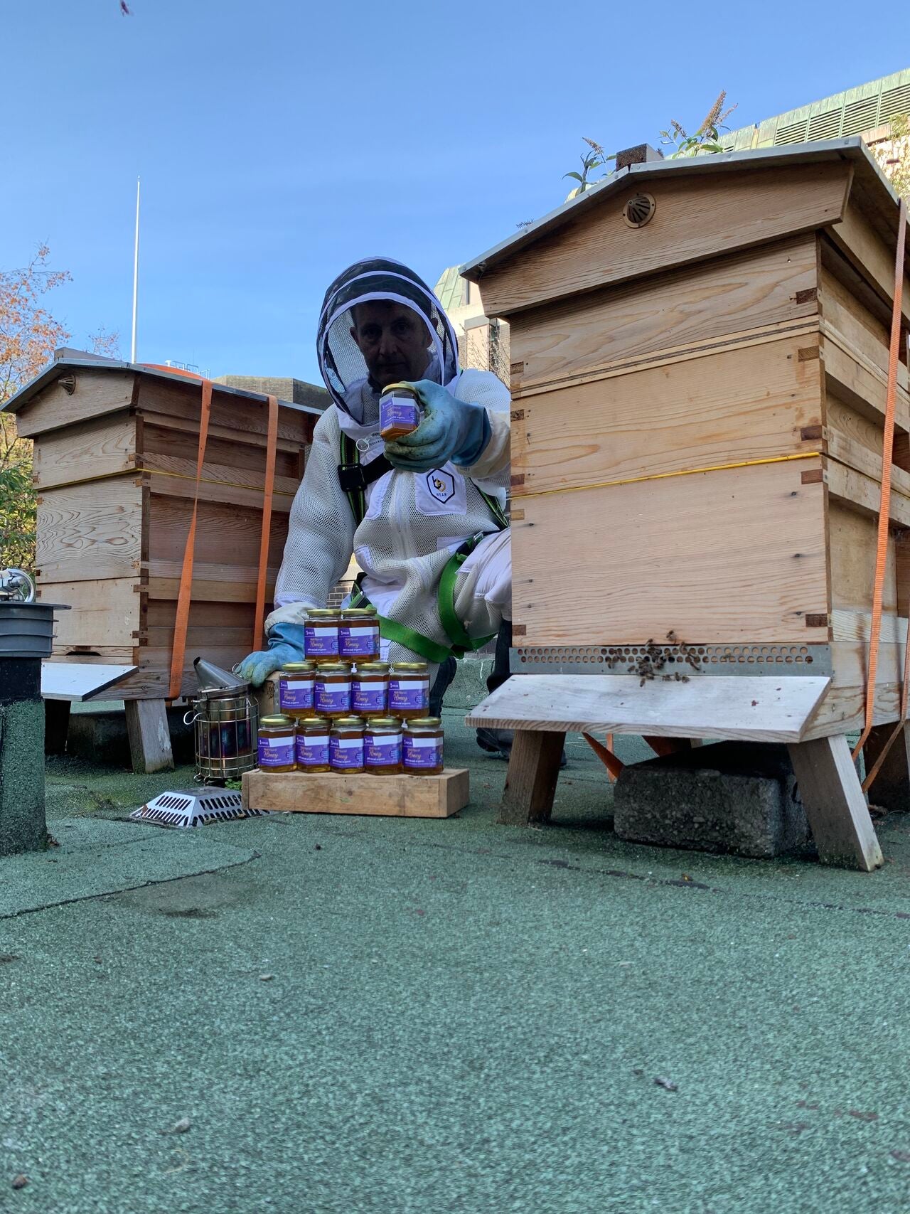 Man in beekeeper suit holds up jar of Irish Life honey