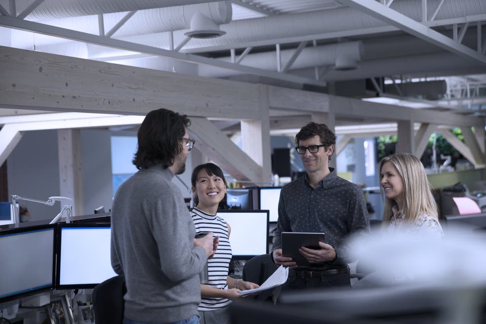 4 people in a group standing in the desk area
