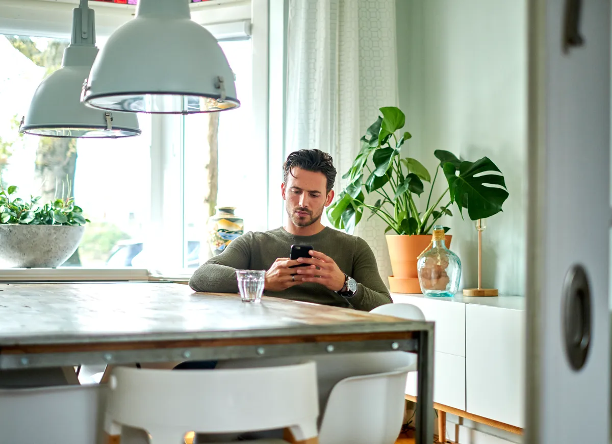 man met telefoon zit aan tafel