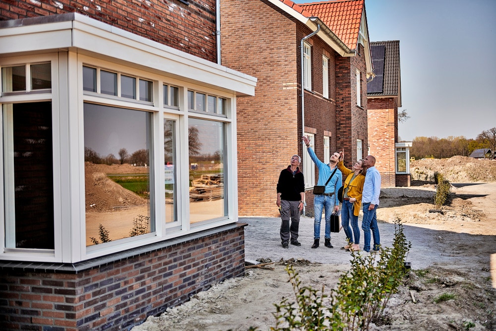 Groep mensen die omhoog wijzen bij nieuwbouwhuis