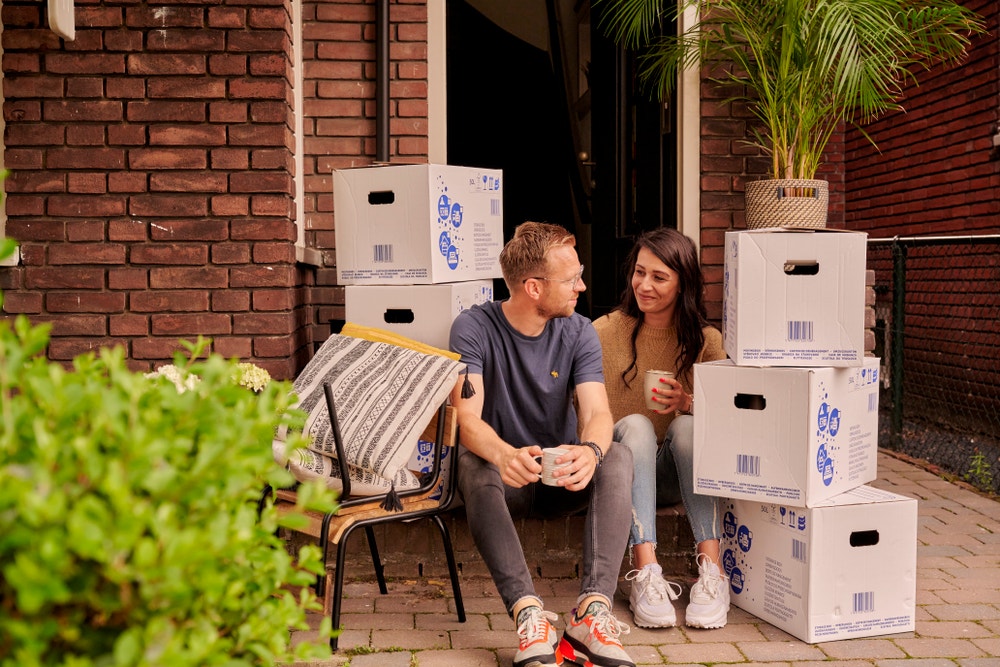 stel zit bij voordeur en verhuisdozen