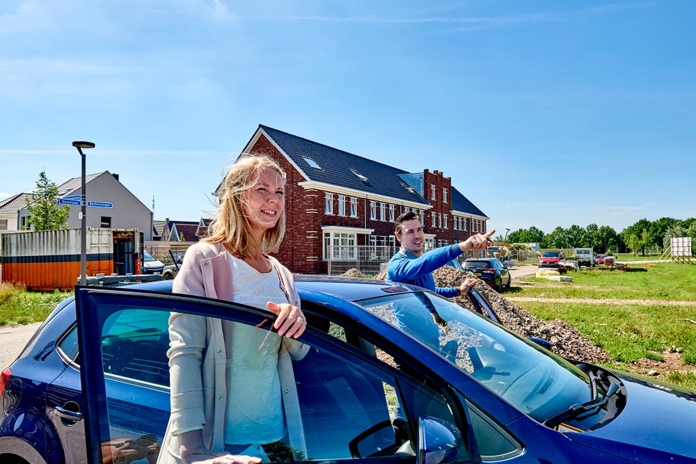 man en vrouw stappen auto uit in wijk in aanbouw