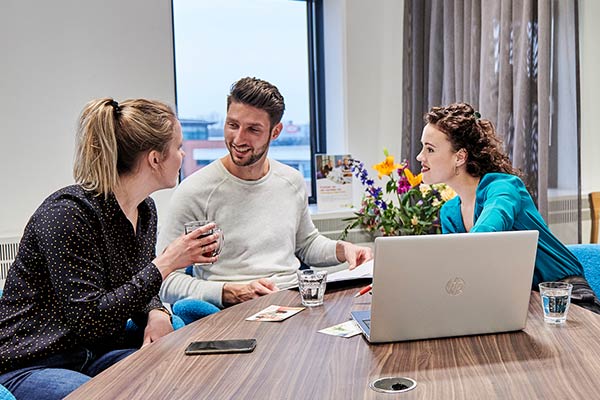twee vrouwen en een man in kantoorruimte aan tafel. Hypotheken en rechtsbijstandverzekering kun je aan tafel doorspreken.