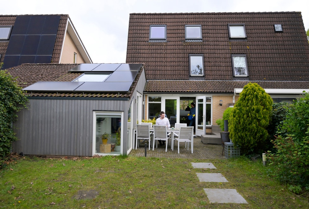 man zit in de tuin achter het huis aan tafel