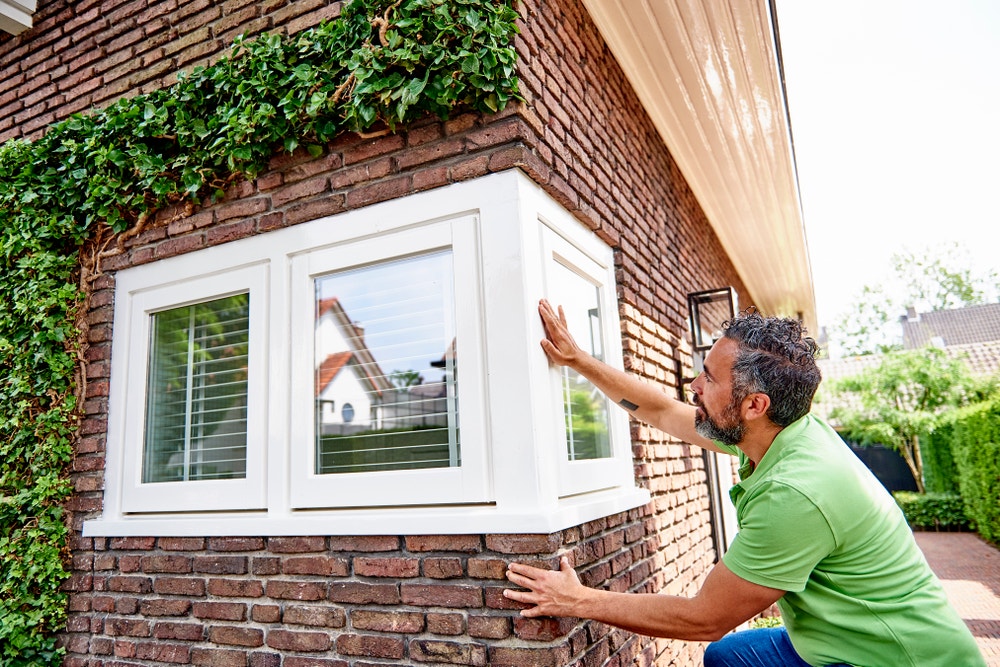 Man controleert kozijn van het huis.