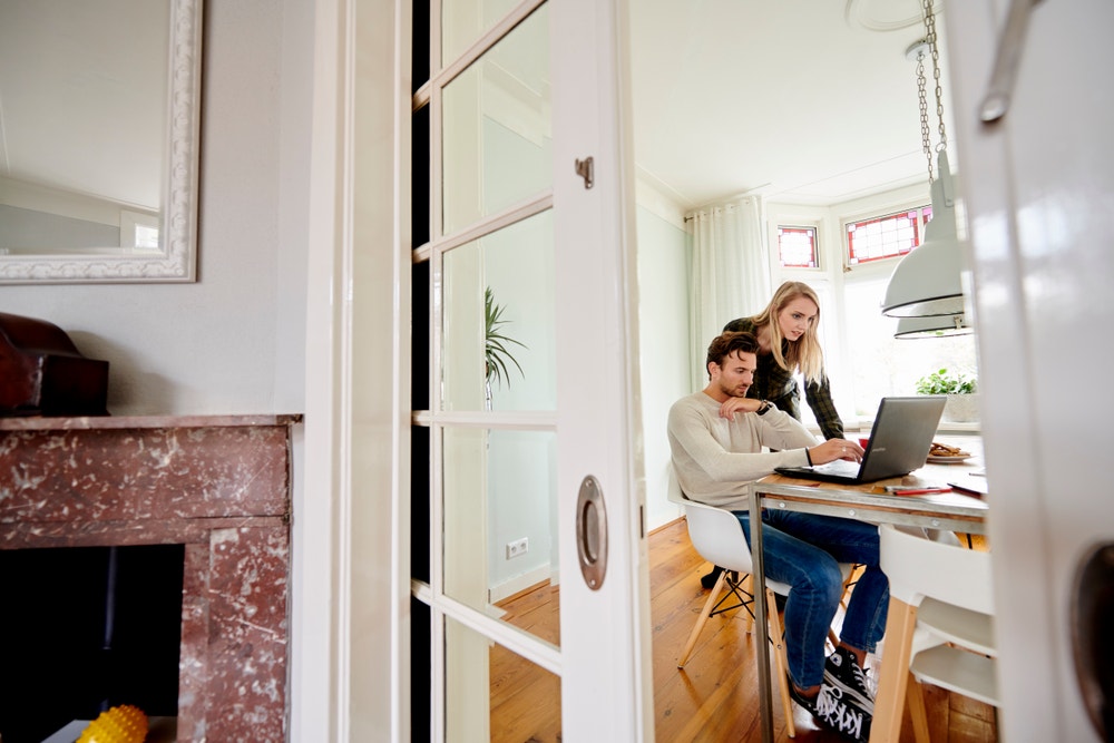 man en vrouw achter laptop in woonkamer