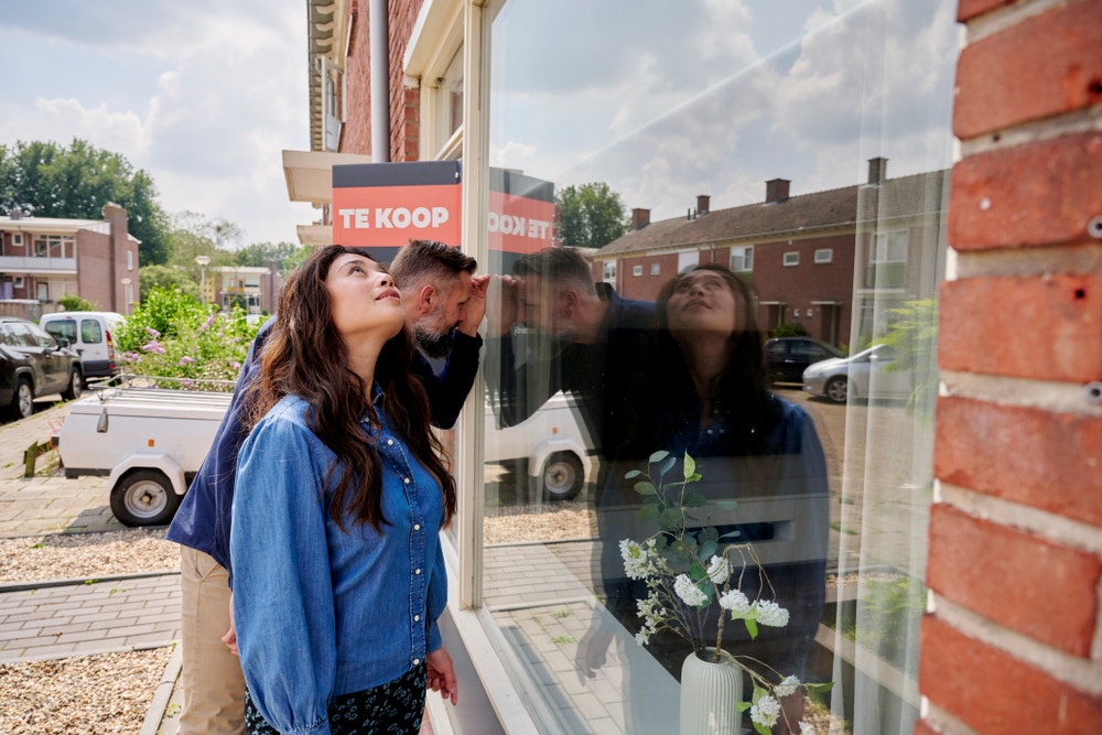 man en vrouw kijken door raam van koophuis