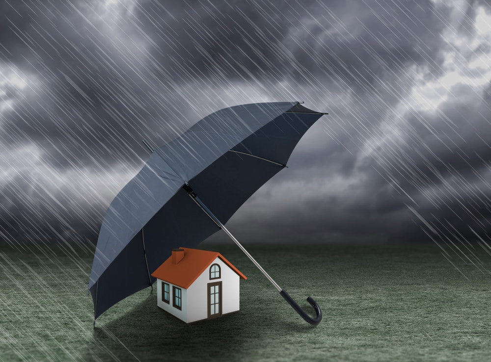 Huis dat beschermd wordt met een paraplu tegen de regen.