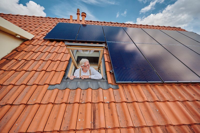 man kijkt uit dakraam naar zonnepanelen