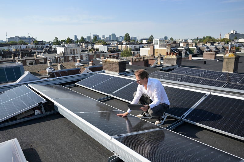 man met tablet bekijkt zonnepanelen op het dak