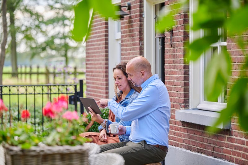 man en vrouw kijken naar tablet in tuin