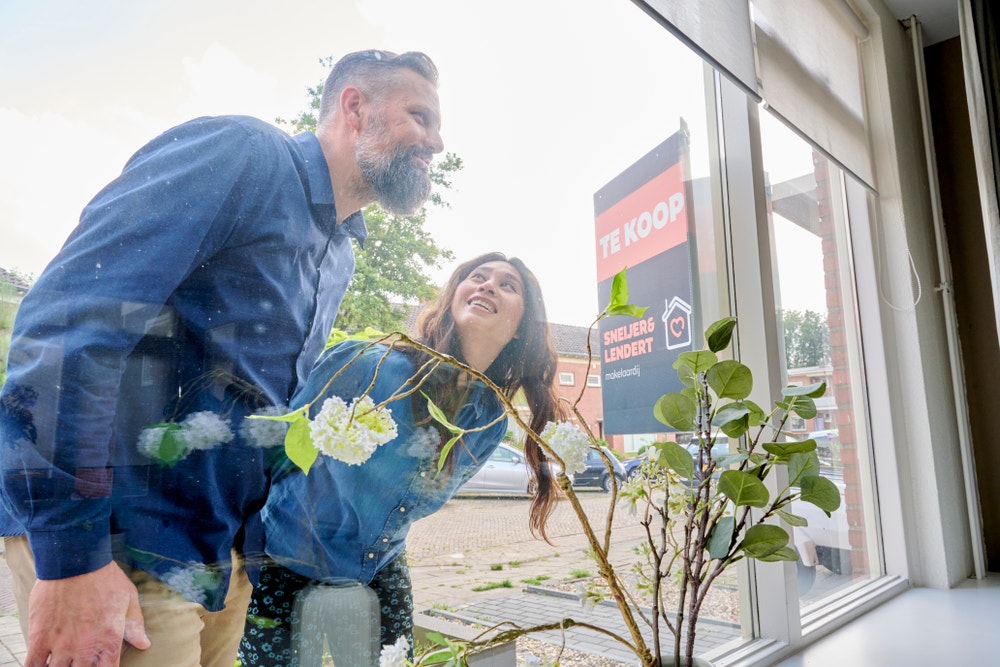 man en vrouw kijken door raam van koophuis