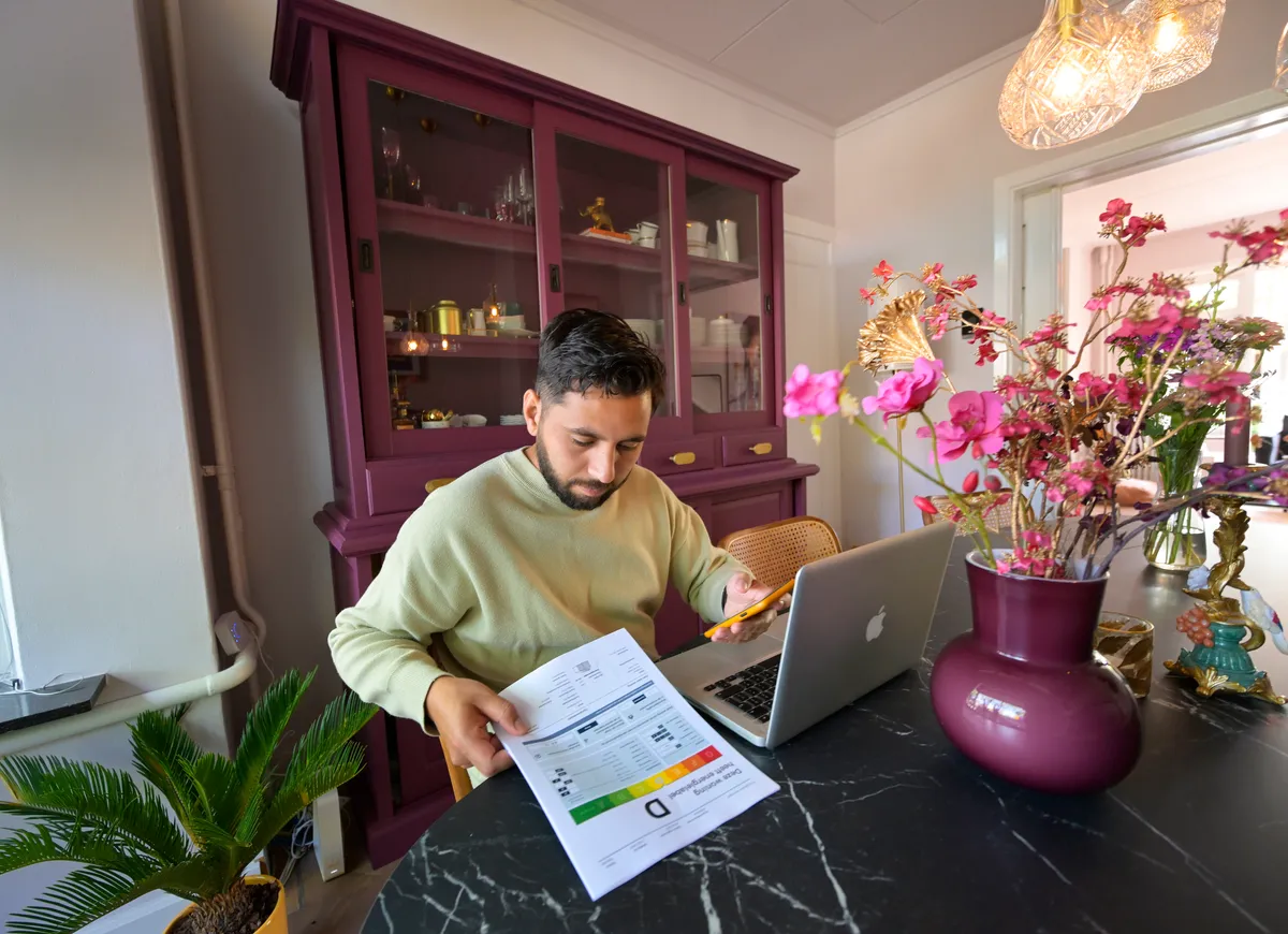man met rapport energielabel achter laptop aan tafel