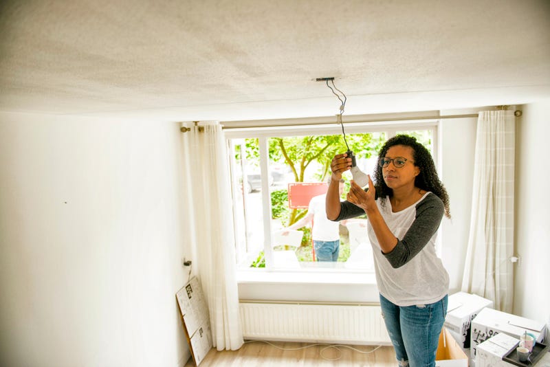 vrouw repareert lamp in woonkamer