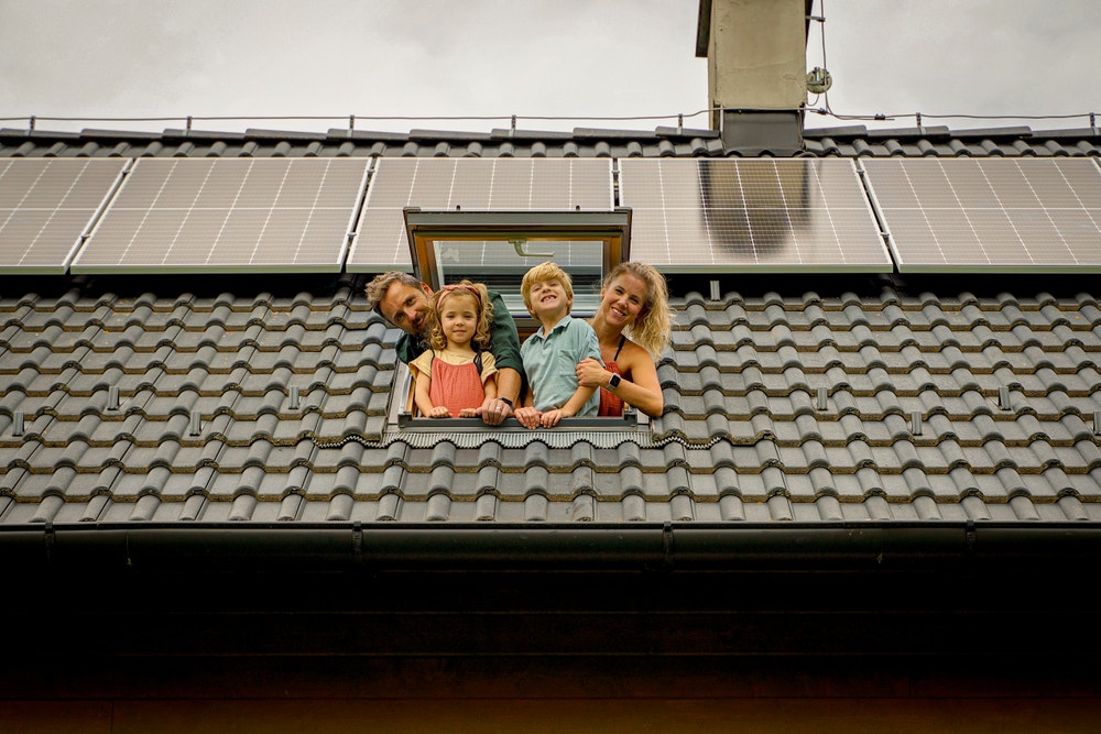 Gezin kijkt uit het dakraam met zonnepanelen.
