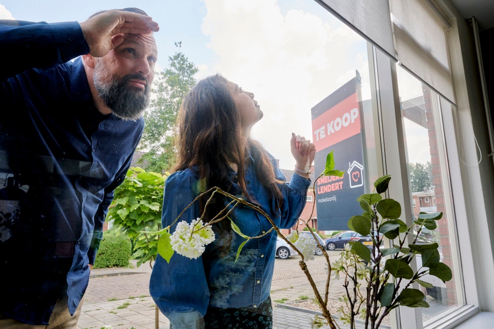 man en vrouw kijken door raam van koophuis