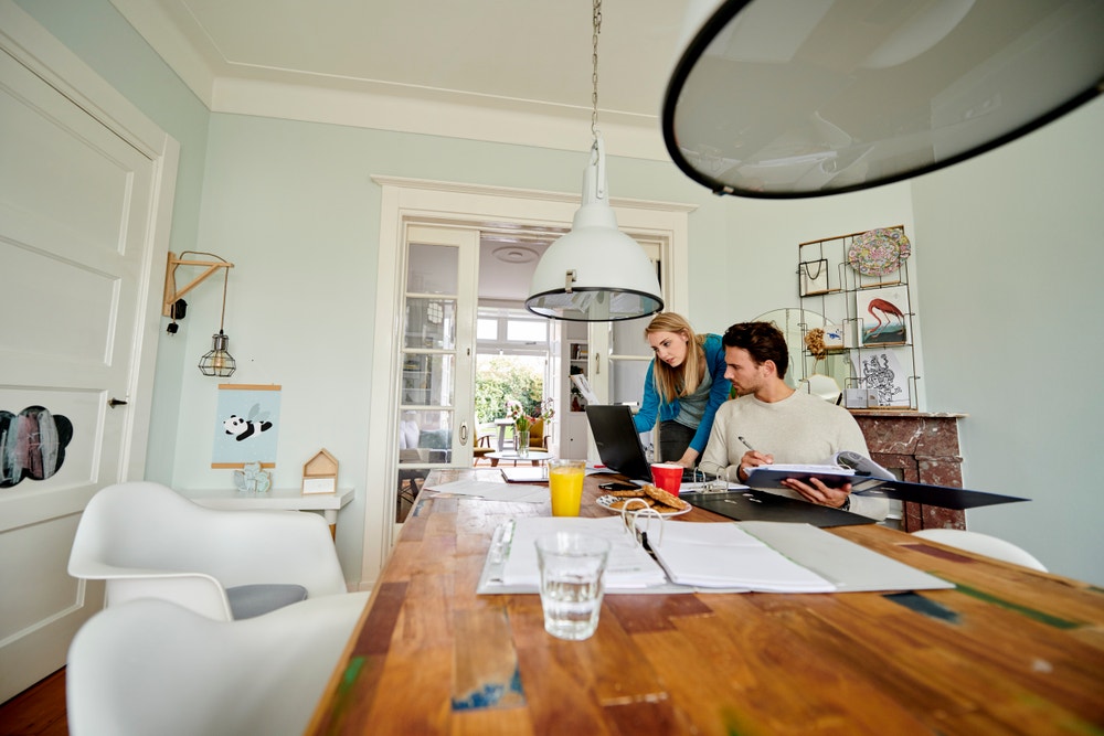 man en vrouw aan tafel met papierwerk en laptop