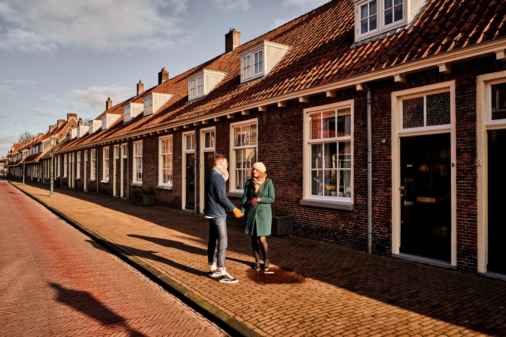 man en vrouw staan bij oude woningen